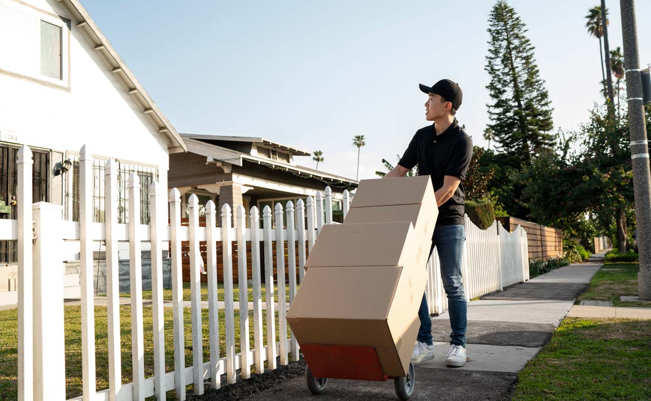 A person moving boxes out of a white villa, representing the need for professional villa move-out cleaning in Dubai